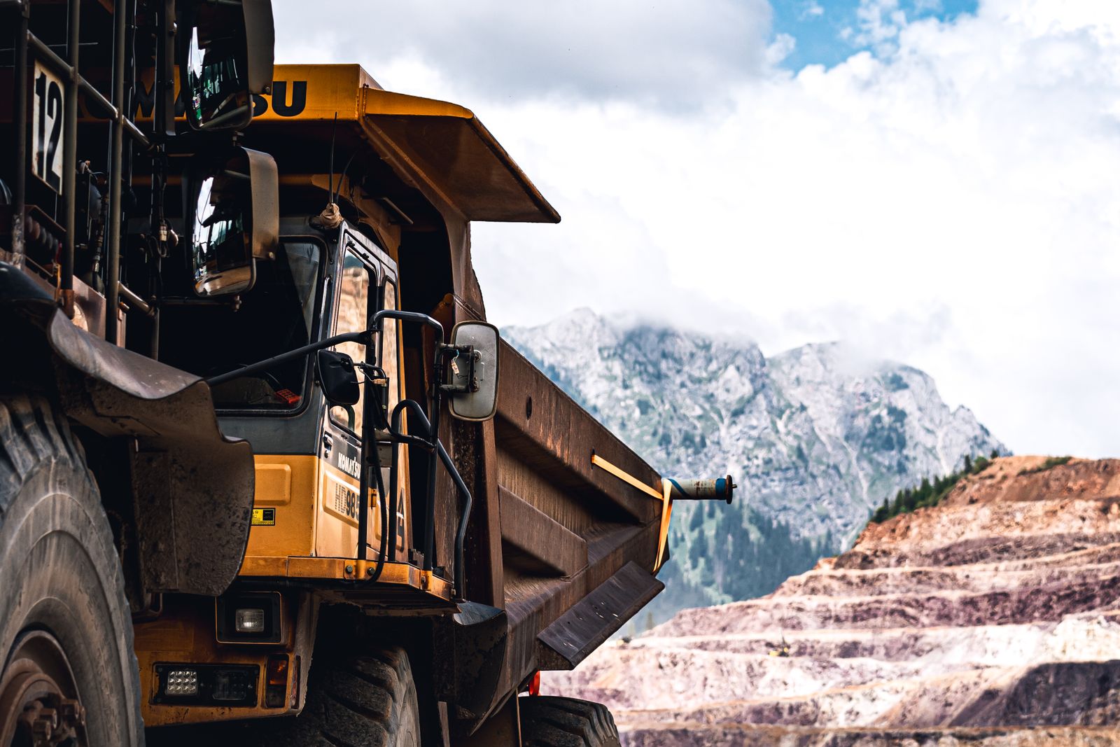 A massive haul truck in a rugged mountain mining landscape