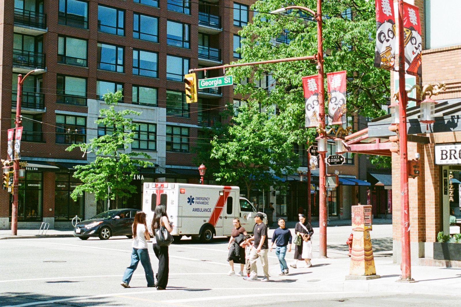 A sunny street scene in Vancouver's Chinatown with pedestrians and storefronts