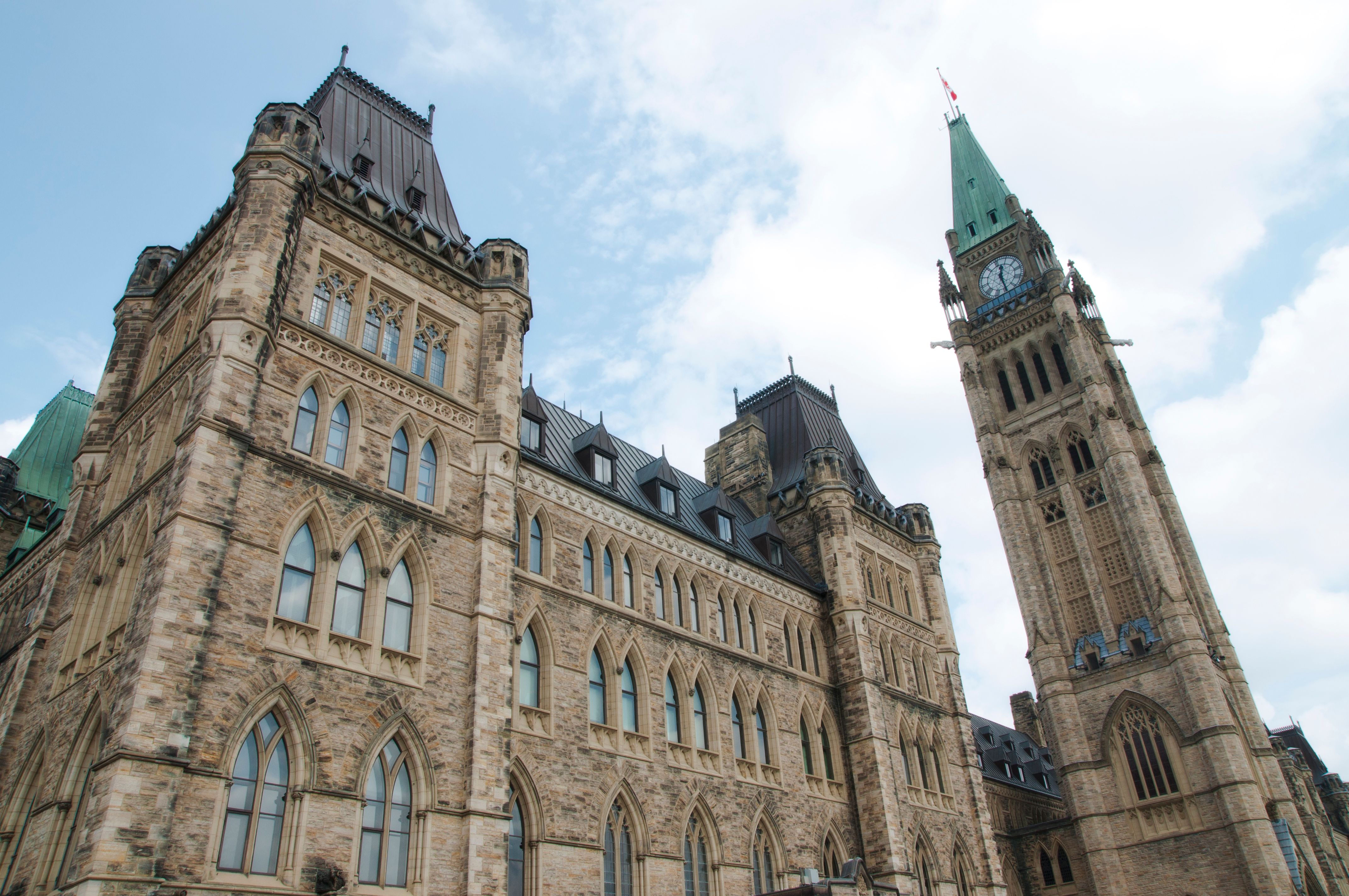 Looking up at Parliament Hill's Peace Tower against a partly cloudy sky