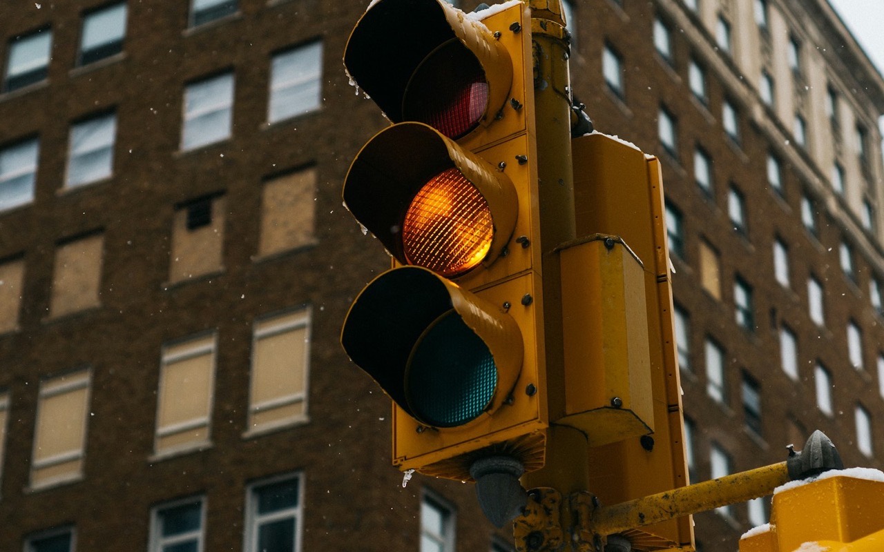 A city traffic light showing amber against an office building
